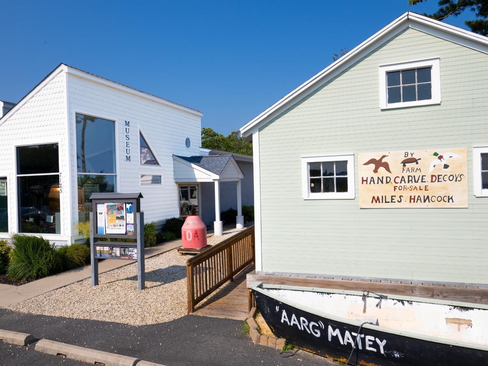 A white two-story building with a sign that includes images of ponies and a small white boat